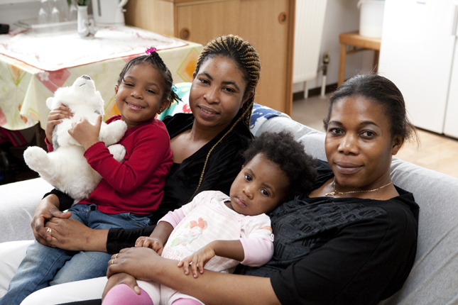 Zwei Frauen sitzen mit ihren Kindern auf einem Sofa in der Flüchtlingsberatung.