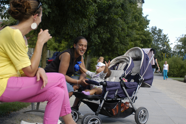 Zwei Frauen bewundern den Nachwuchs im Kinderwagen. 