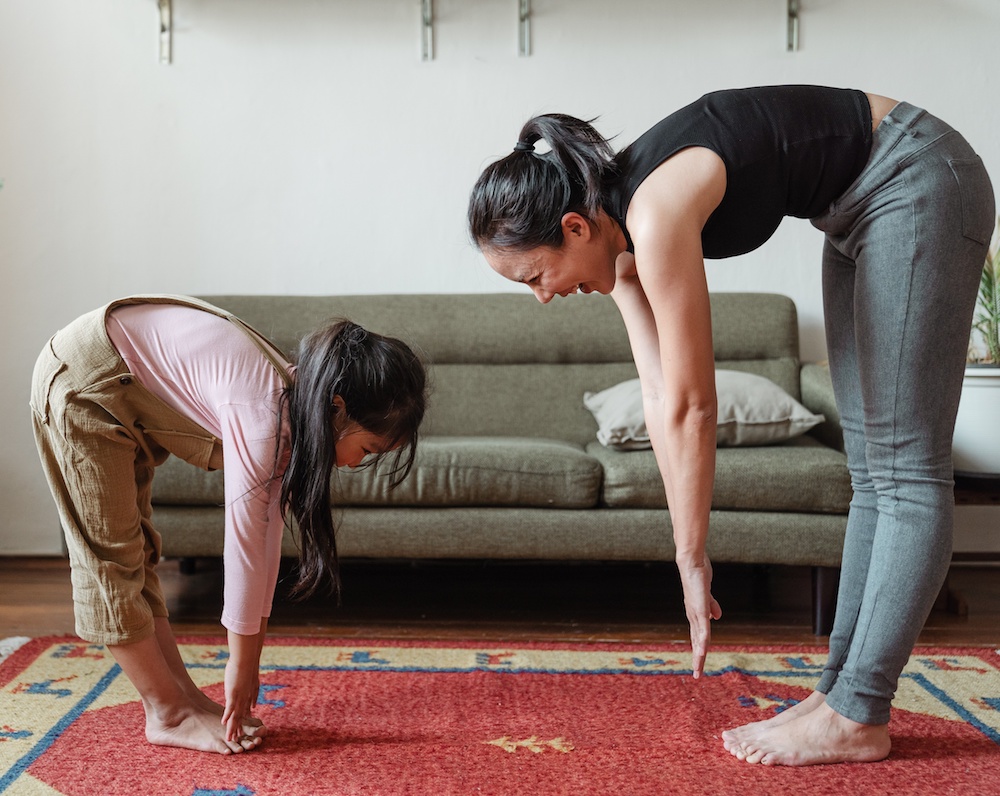 Frau macht mit ihrem Kind Yoga-Übungen