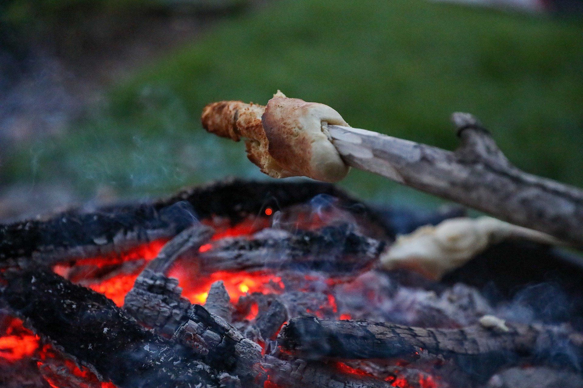 Ein Stück Brot wird über einem Lagerfeuer geröstet