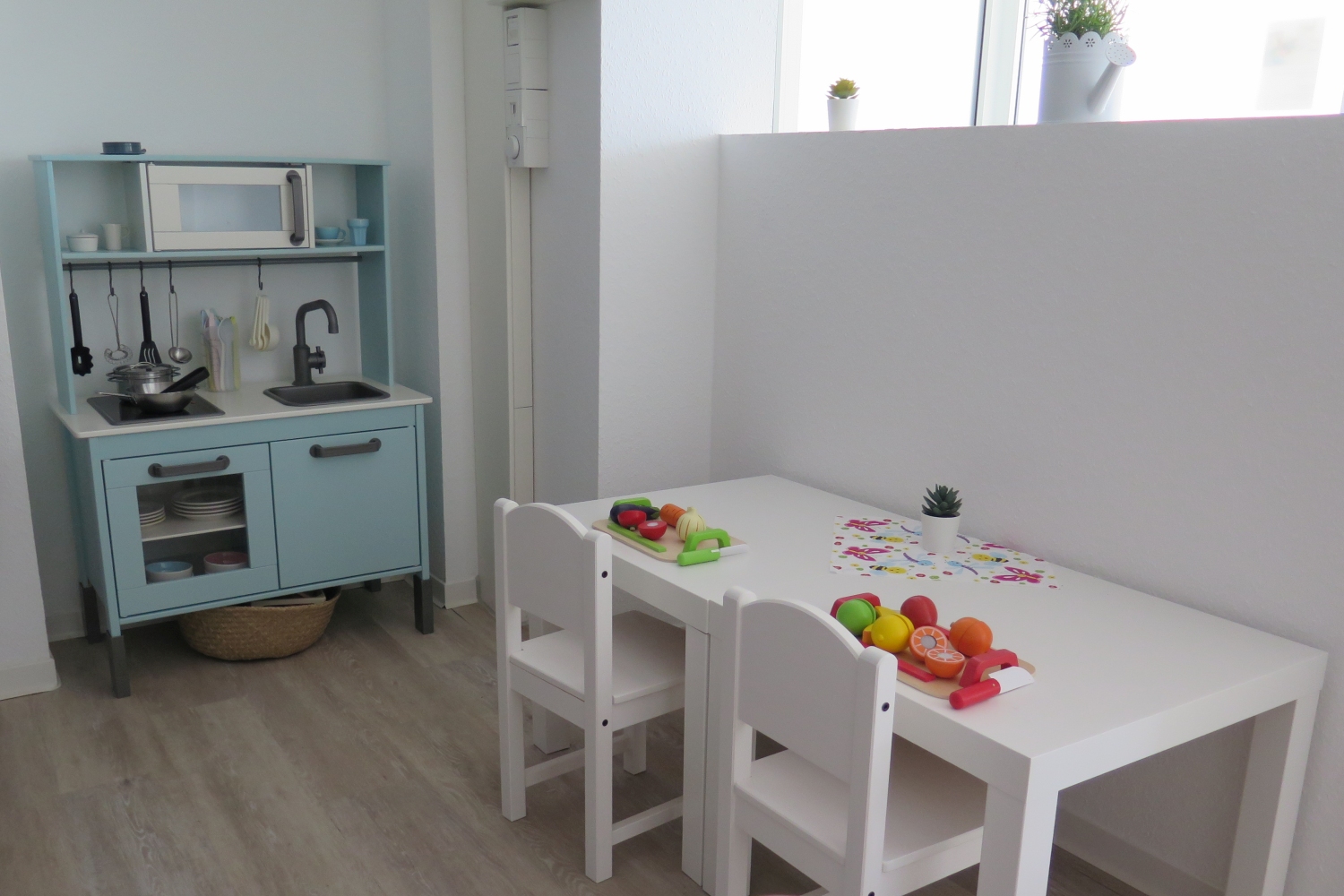 Kinderküche und Tisch mit Kinderstühlen stehe in einem Raum