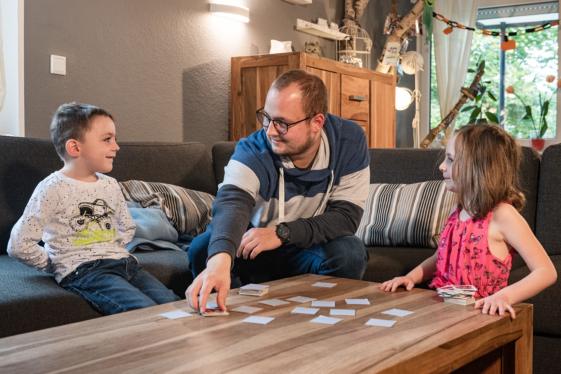 Ein Betreuer sitzt mit zwei Kindern an einem Tisch in einer Wohngruppe