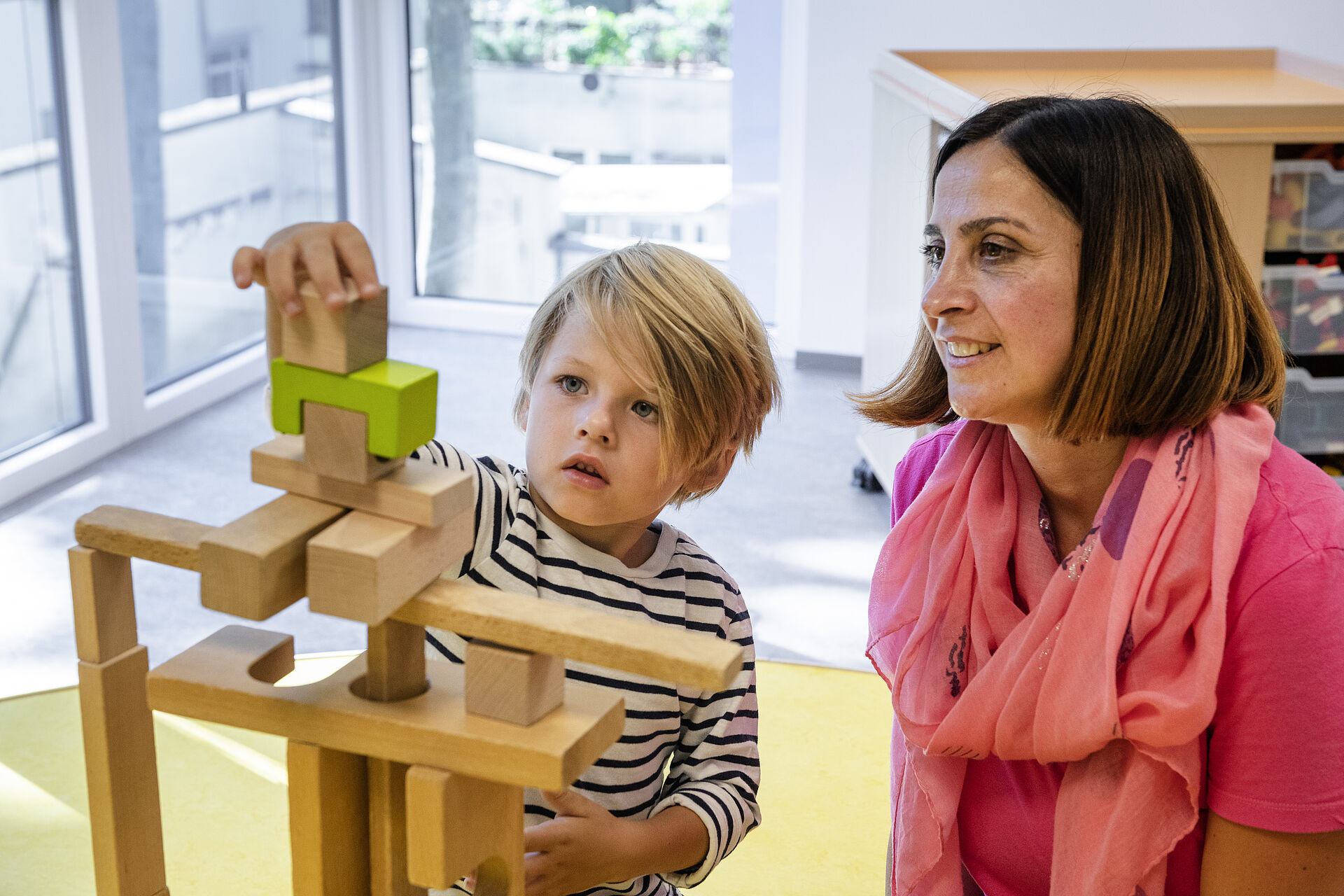 Eine Erzieherin baut etwas mit Holzklötzen mit einem Jungen