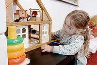 Mädchen spielt mit Puppenhaus
