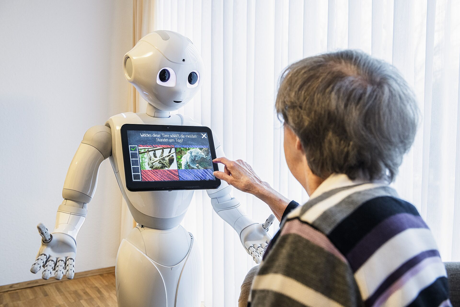 Eine Pflegeheim-Bewohnerin im Kontakt mit Roboter Pepper