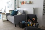 Ein helles Zimmer mit Sofa und Puppen
