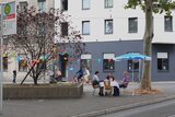 Wohnungslose Menschen picknicken vor dem café pur. 