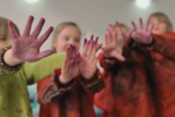 Kinder zeigen ihre bunten Hände.