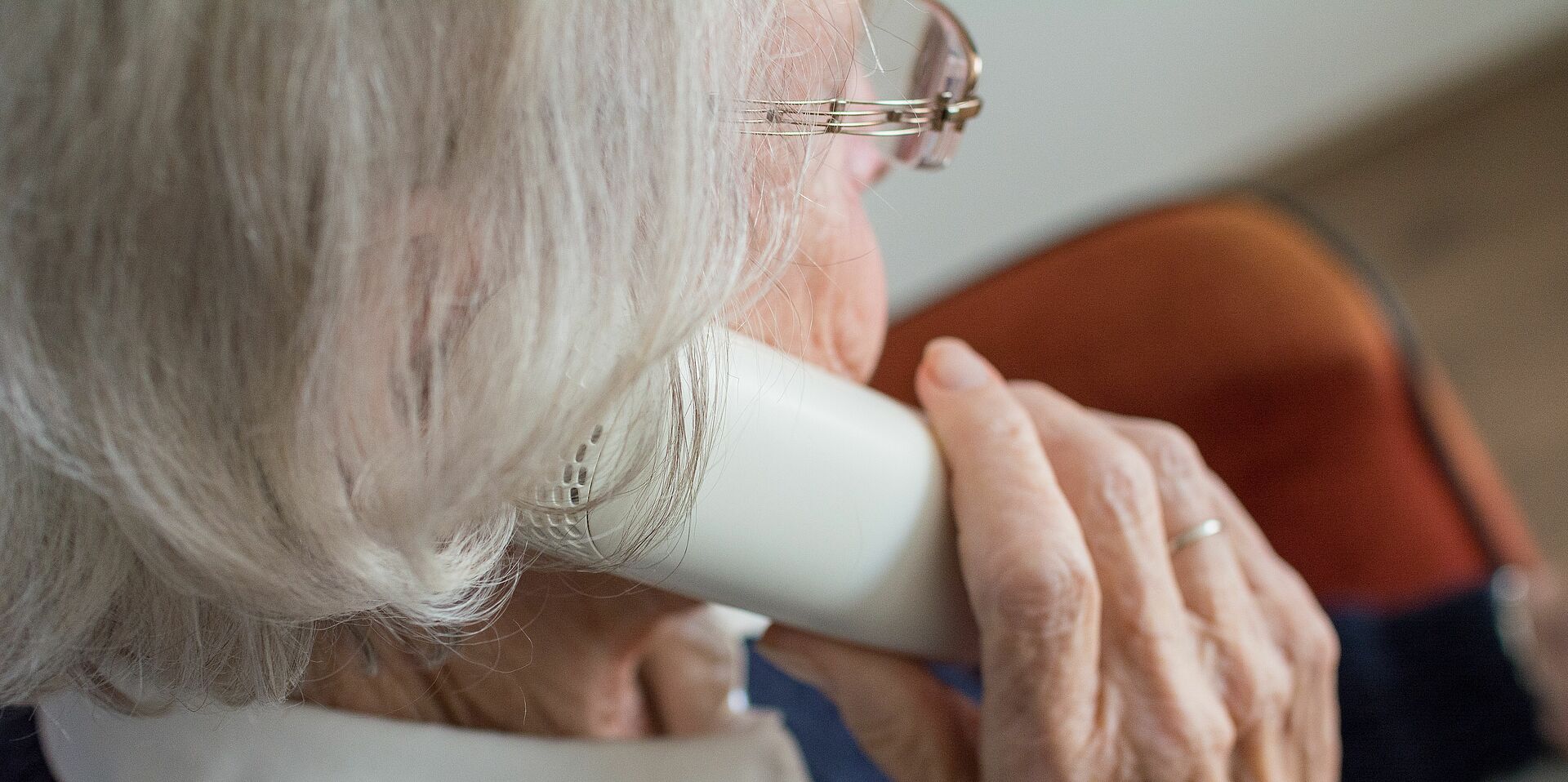 Eine alte Dame hält einen Hörer an ihr Ohr