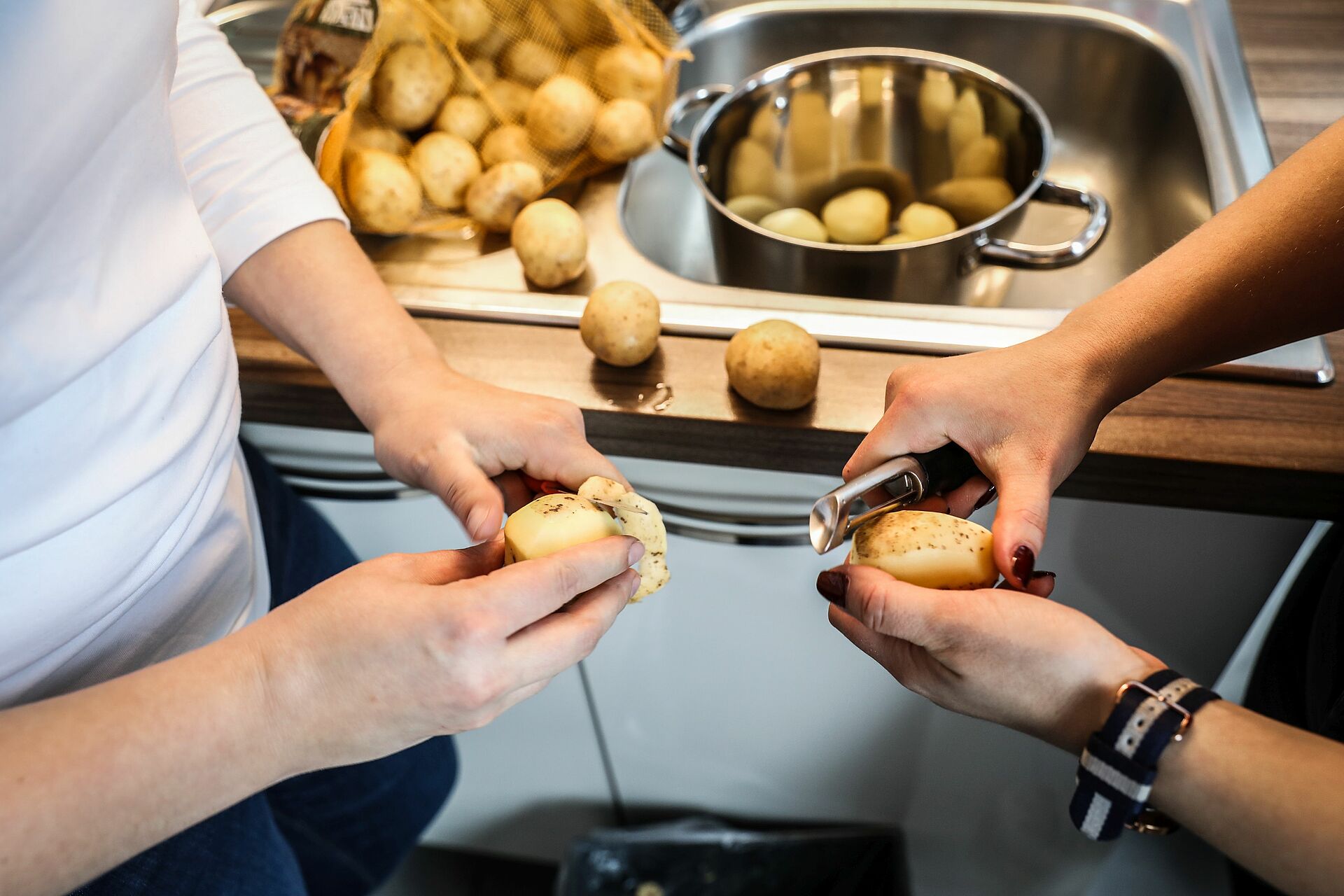 Zwei Personen schälen Kartoffeln