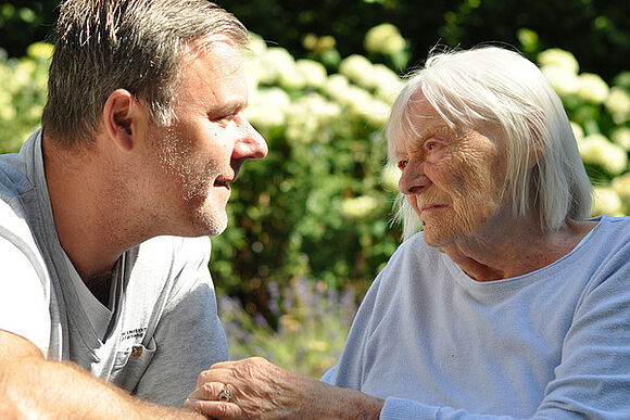 Eine alte Dame mit ihrem Pfleger im Garten