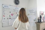 Ein Mädchen steht vor dem Planungskalender einer Wohngruppe.