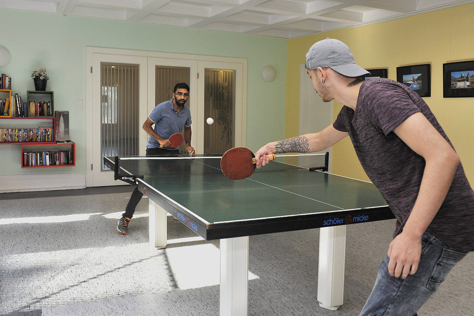 Bewohner des Naumann-Hauses spielen Tischtennis im Sportraum. 