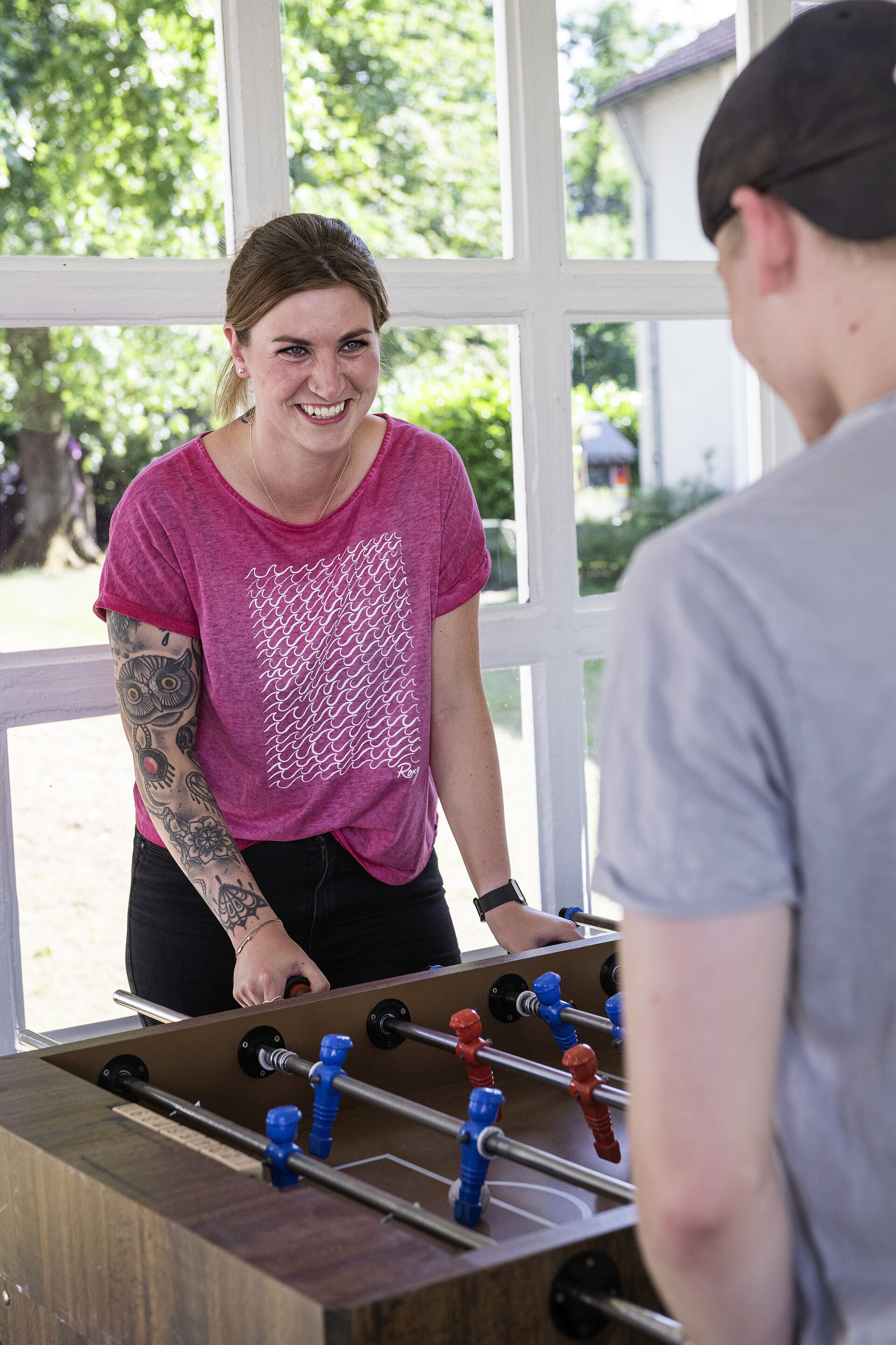 Frau spielt mit Jugendlichem Kicker