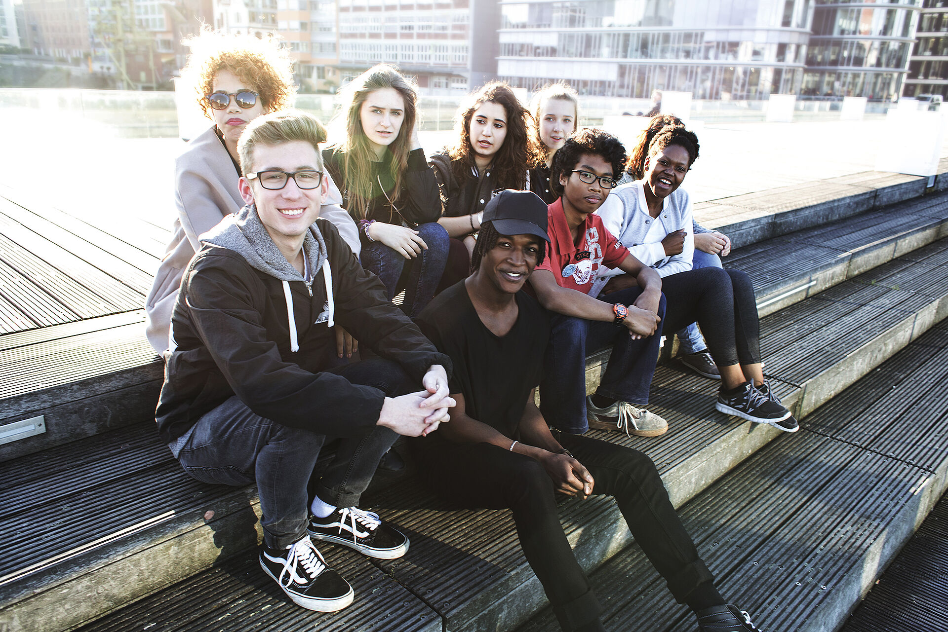 Jugendliche des Jugendmigrationsdienstes sitzen auf einer Bank am Rheinufer. 