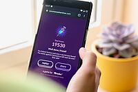 Hand tippt auf Handy mit Corona-Spiel