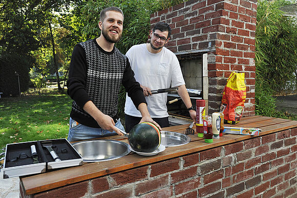 Zwei Bewohner des Friedrich-Naumann-Hauses grillen im Garten.